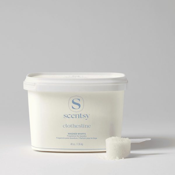 Cream-coloured tub of Scentsy Clothesline Washer Whiffs Tub with white lid and a measuring scoop filled with white granules beside it