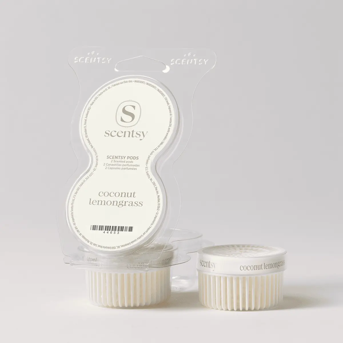 Two cream-coloured Scentsy Pods with vertical ridged sides in their clear plastic clamshell packaging, labelled Coconut Lemongrass Scentsy Pods, with branded hang tabs and product information visible on the blister card.