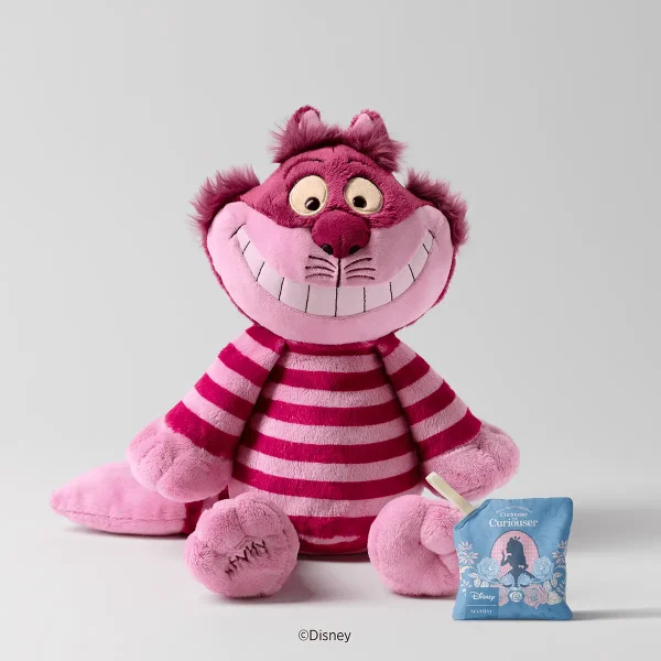 Pink and magenta striped plush with a wide toothy grin and fuzzy ears, the Cheshire Cat Scentsy Buddy, sitting beside a blue floral Scent Pak