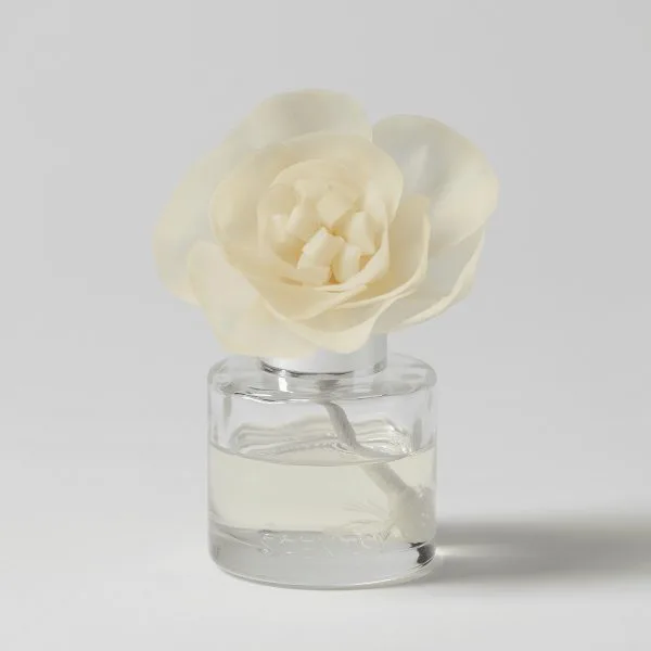 Cream-coloured fabric flower with layered petals and white wax cubes at the centre, displayed in a clear glass diffuser bottle filled with pale liquid, the Luna - Buttercup Belle Fragrance Flower