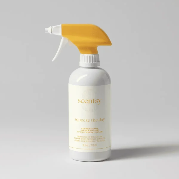 White spray bottle with gold trigger and cap, white label with gold text reading "Scentsy Squeeze the Day Bathroom Cleaner", 16 fl oz size