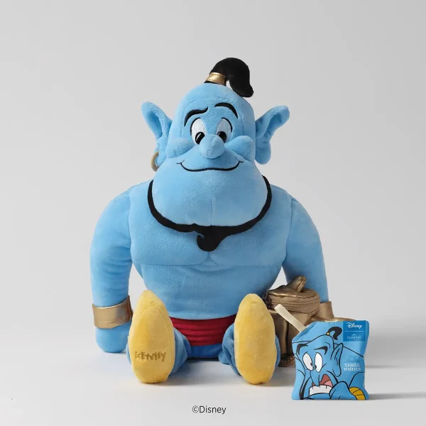 Blue plush Genie character with pointed ears, gold wrist cuffs, red pants, black hair topknot, smiling expression, yellow feet with "SCENTSY" embroidered detail, the Disney Genie Scentsy Buddy, shown with its blue tag and tan pouch accessory