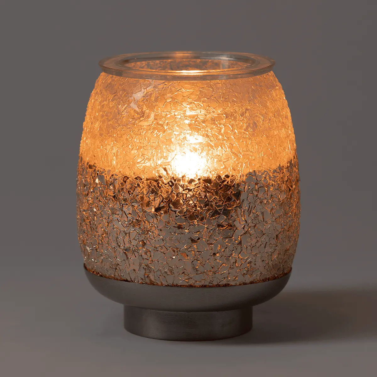 Illuminated warmer with a two-tone textured glass vessel in copper and bronze tones, topped with a metal rim, seated on a dark base, the Glisten Scentsy Warmer