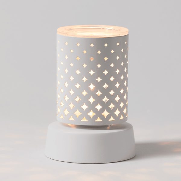White cylindrical ceramic warmer with a repeating four-pointed star cutout pattern that glows warmly when lit, sitting on a matching white cylindrical tabletop base, the Light From Within Mini Scentsy Warmer with Tabletop Base