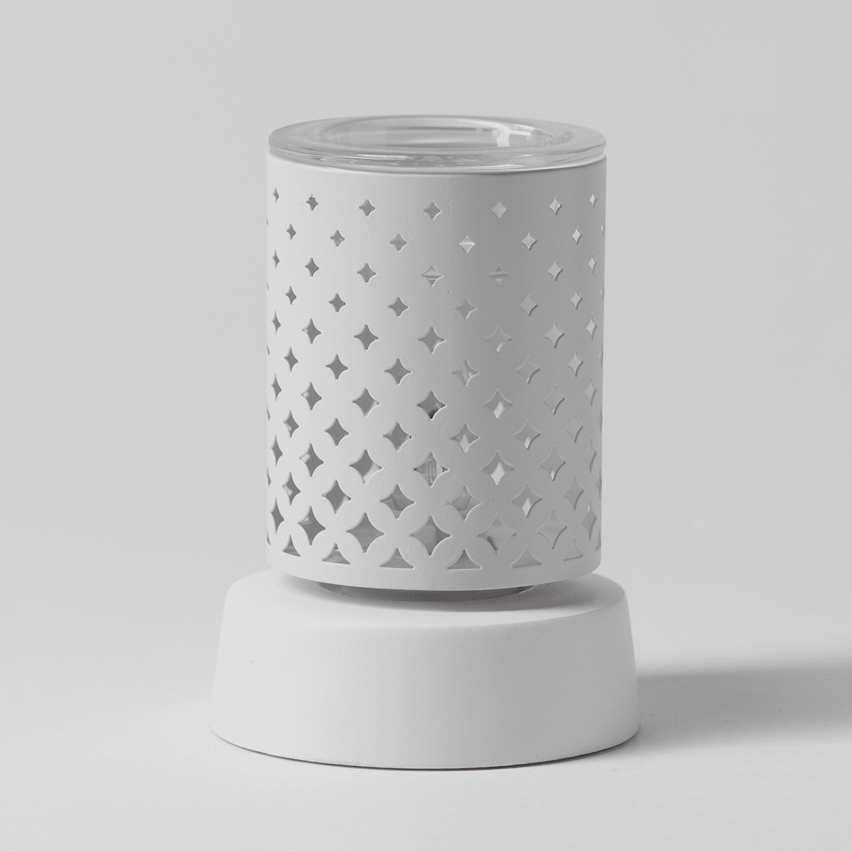 White cylindrical warmer with perforated four-pointed star pattern, clear glass top, and matching white ceramic base, the Light From Within Mini Scentsy Warmer