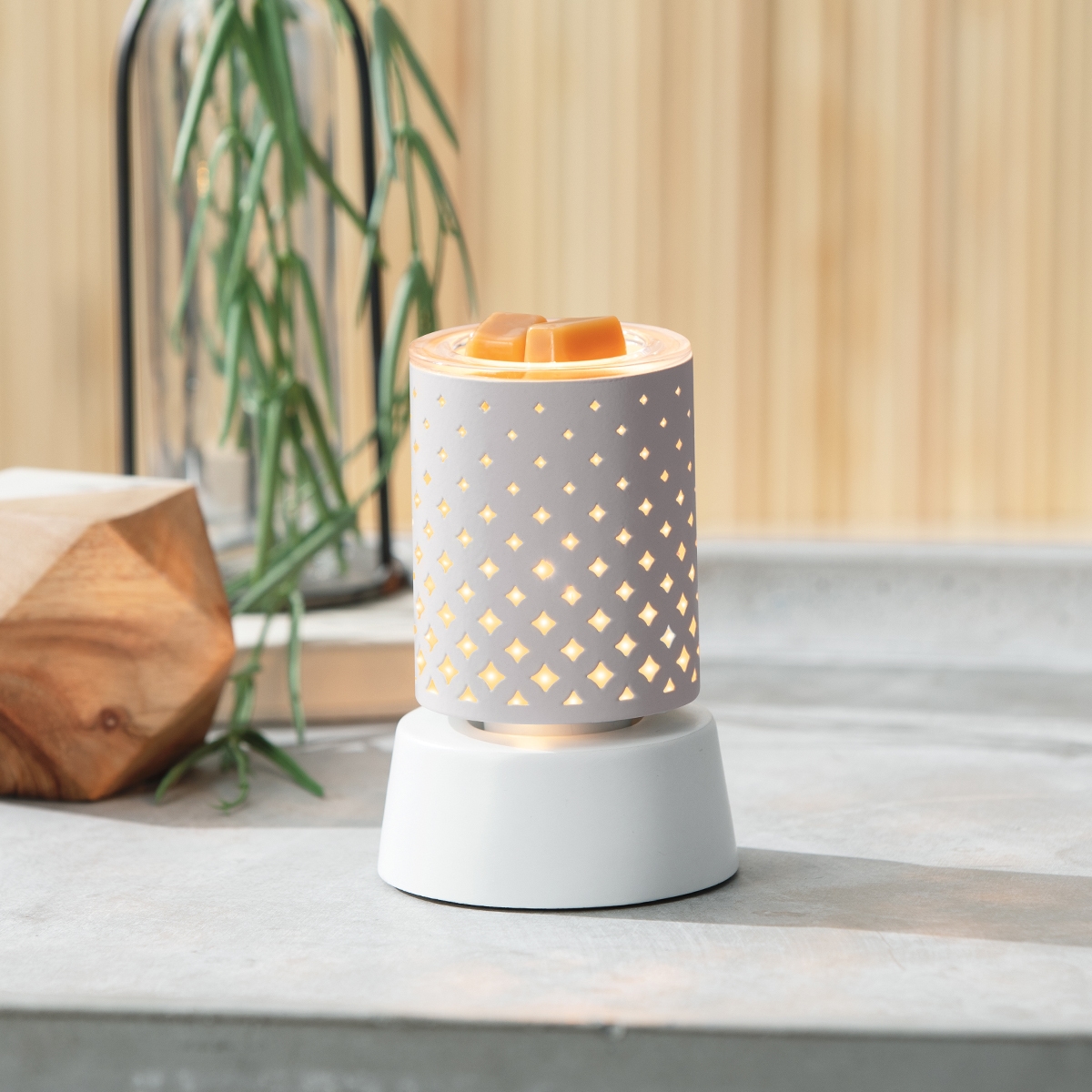 Grey ceramic mini warmer with a perforated diamond pattern and white base, topped with an amber wax cube, the Light From Within Mini Scentsy Warmer with Tabletop Base