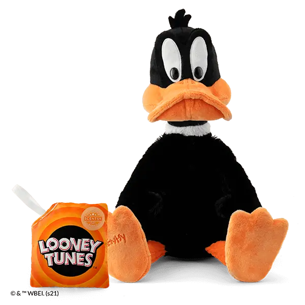 Daffy Duck Scentsy Buddy plush toy with black fuzzy body, white eye patches with black pupils, orange bill and feet, shown seated with an orange scent pak beside it