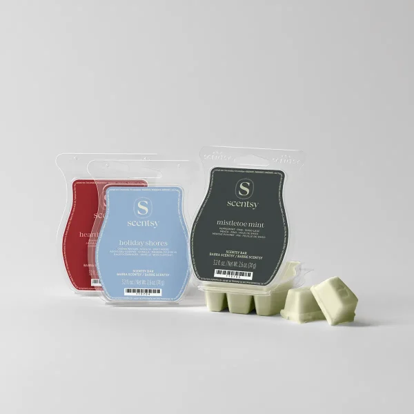 Three Scentsy Bars in red, light blue, and dark green packaging displayed with pale green wax melts scattered in front, the Holiday Scentsy Bar 3-pack