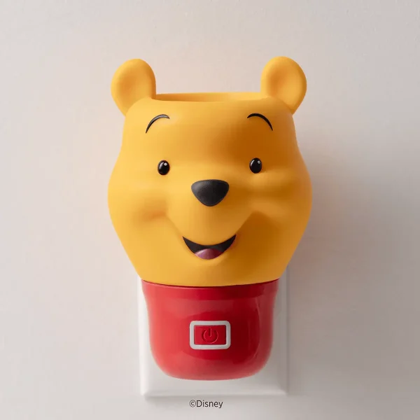 Yellow Winnie the Pooh head with smiling face and round ears atop a red base with power button, the Winnie the Pooh Scentsy Air Fan Mini+ plugged into a white wall outlet