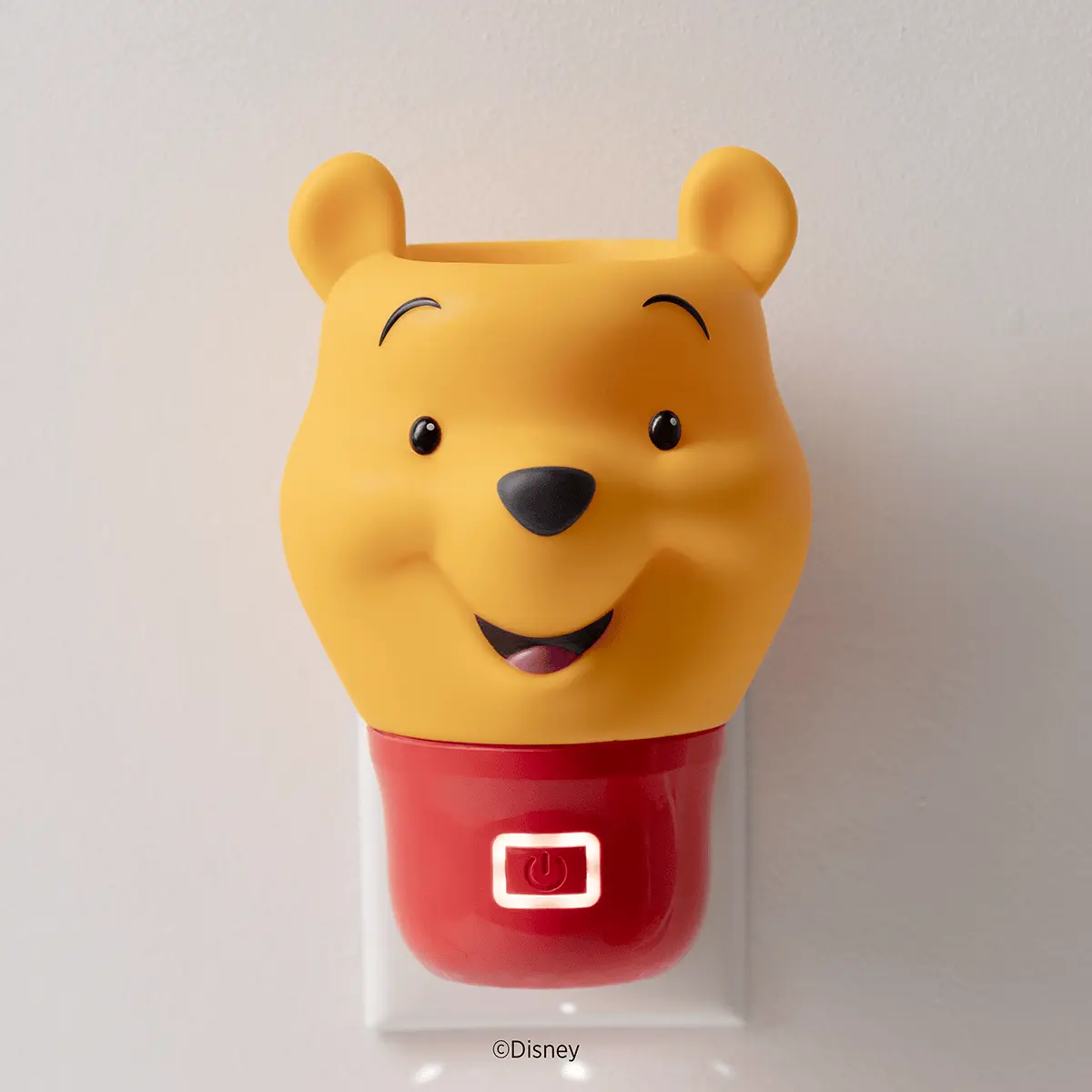 Plug-in yellow Winnie the Pooh head with a smiling face and round ears on a red base with an illuminated power button