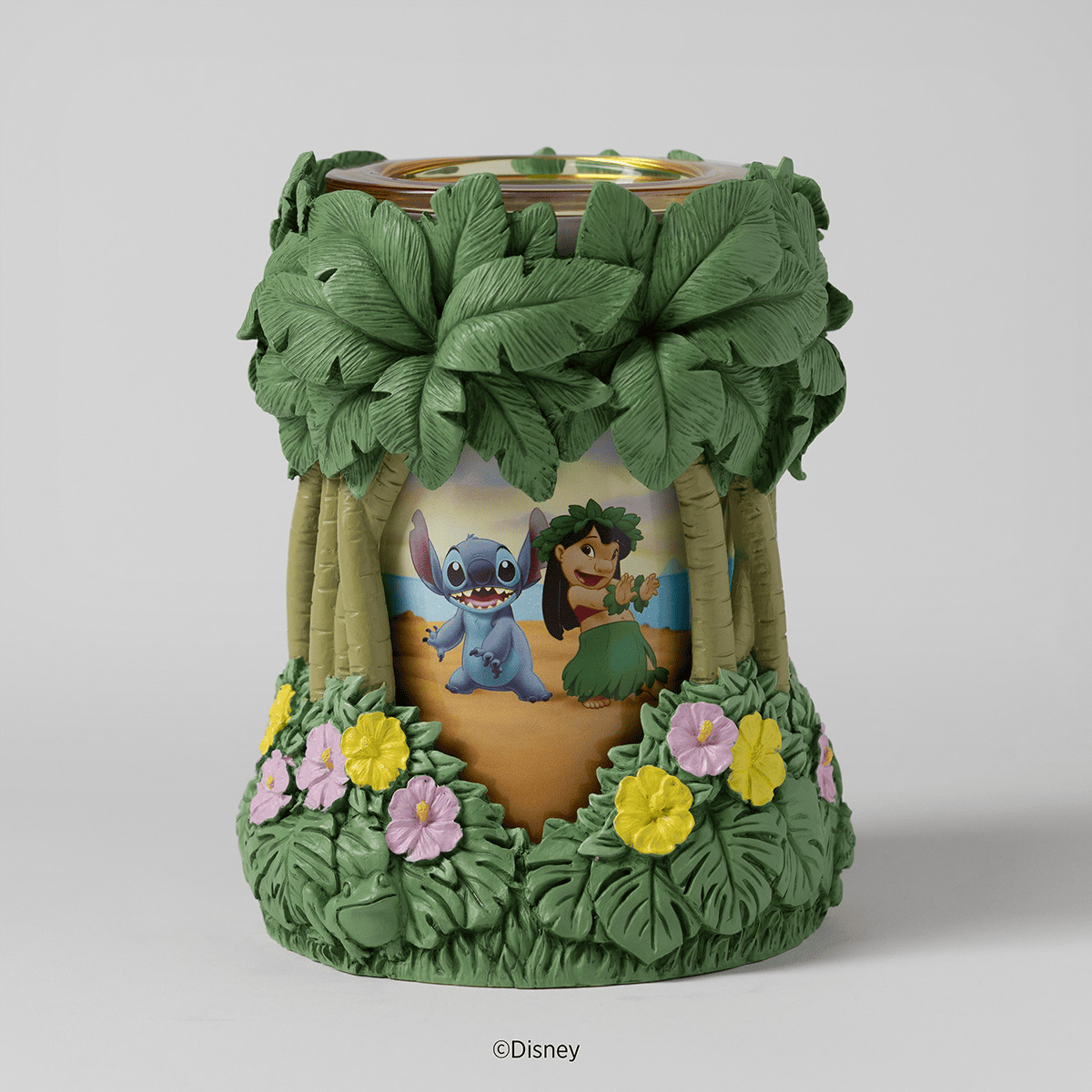 Cylindrical Scentsy warmer with a tropical island scene featuring Lilo and Stitch under palm trees, surrounded by pink and yellow flowers, with a wooden-look rim at the top