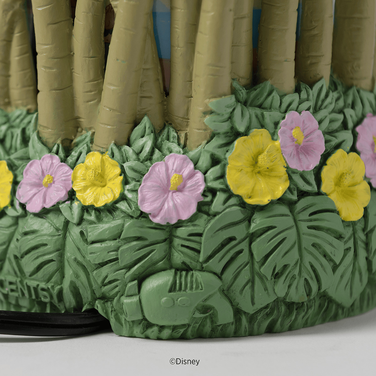 Ceramic warmer base featuring green tropical leaves with pink and yellow hibiscus flowers and a carved tiki mask detail, topped with tan bamboo stalks, the Disney Lilo & Stitch: Aloha-Ohana Scentsy Warmer