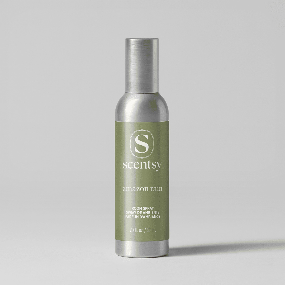 Brushed silver aerosol bottle with an olive green label, the Amazon Rain Room Spray, shown upright against a pale grey background