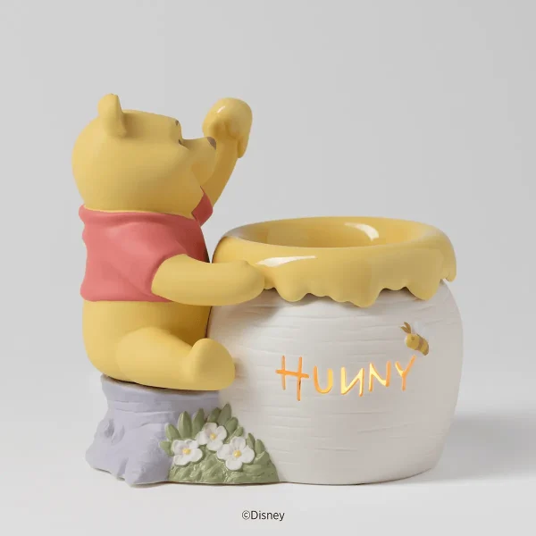 Yellow ceramic Winnie the Pooh figure in a red shirt holding a honey pot-shaped warmer with "HUNNY" text, small white flowers and blue base detail, the Just a Smackerel of Hunny Scentsy Warmer