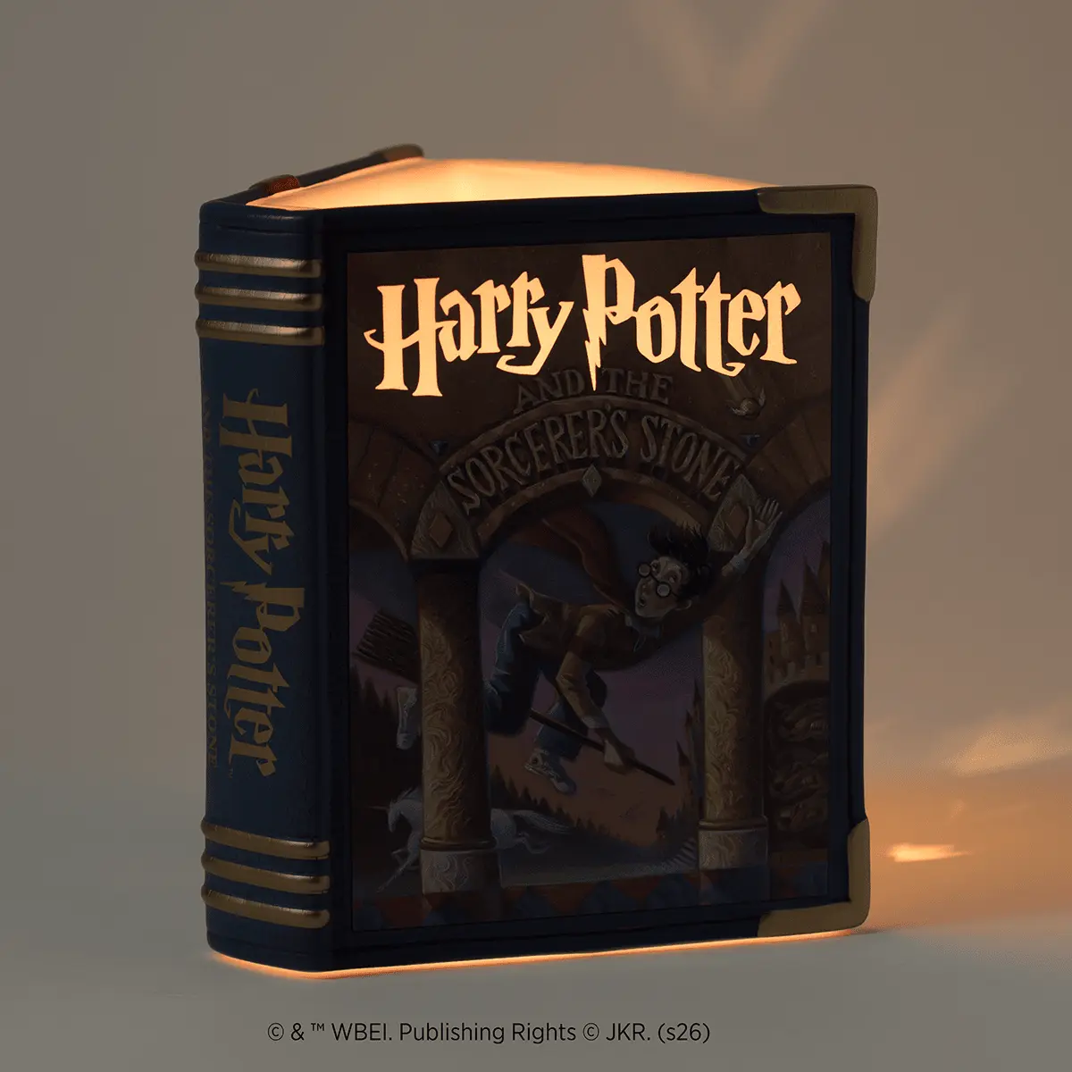Black book-shaped warmer designed as Harry Potter and the Sorcerer's Stone, with gold lettering and brass-coloured metal bands, glowing warmly when lit
