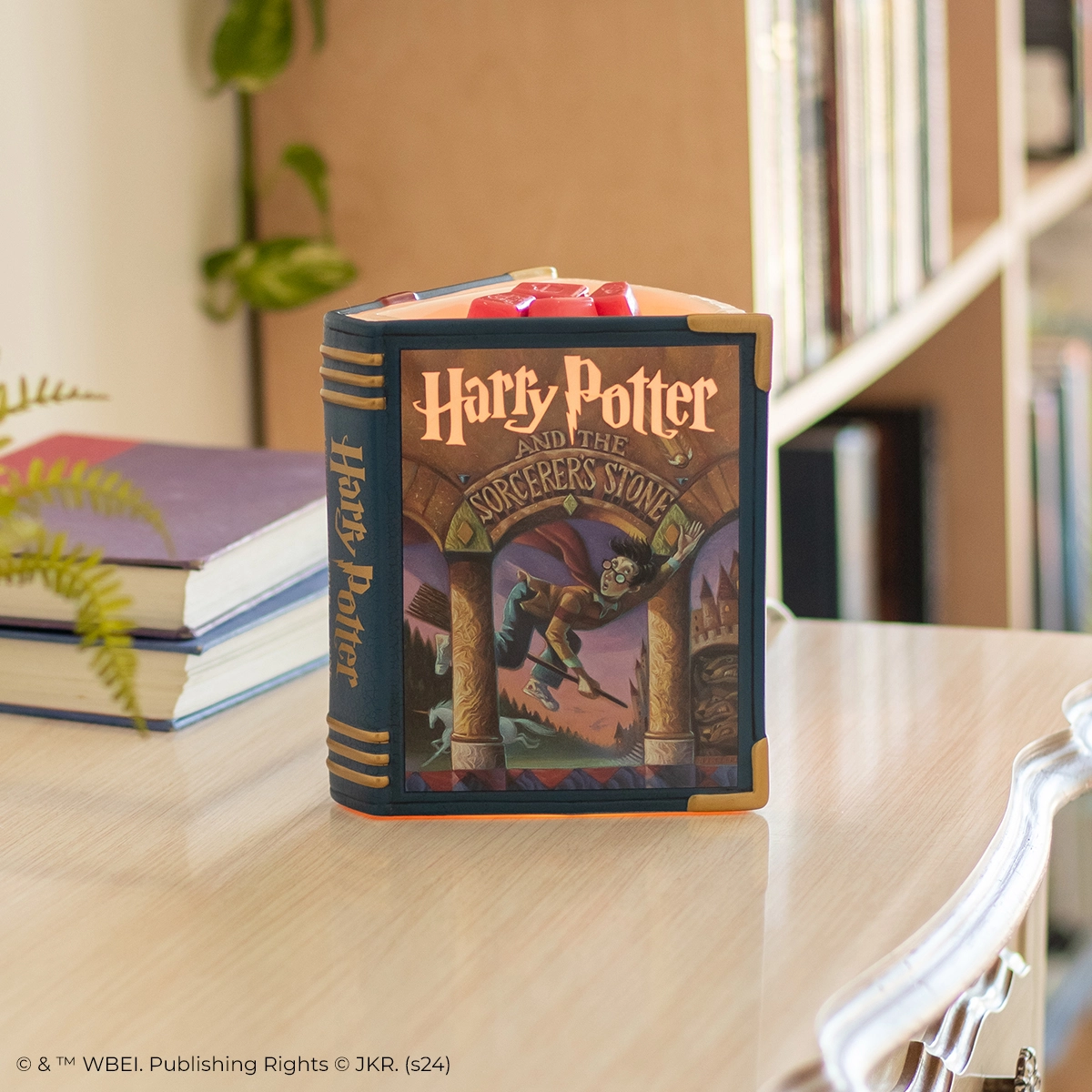 Book-shaped Scentsy Warmer designed to resemble the Harry Potter and the Sorcerer's Stone cover, with navy spine, gold lettering, and illustrated front panel, topped with red wax