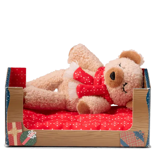 Tan plush bear with a red bow tie lying in a wooden bed with red patterned bedding and blue striped pillows, Cranberry the Bear Scentsy Beddy-Bye Buddy