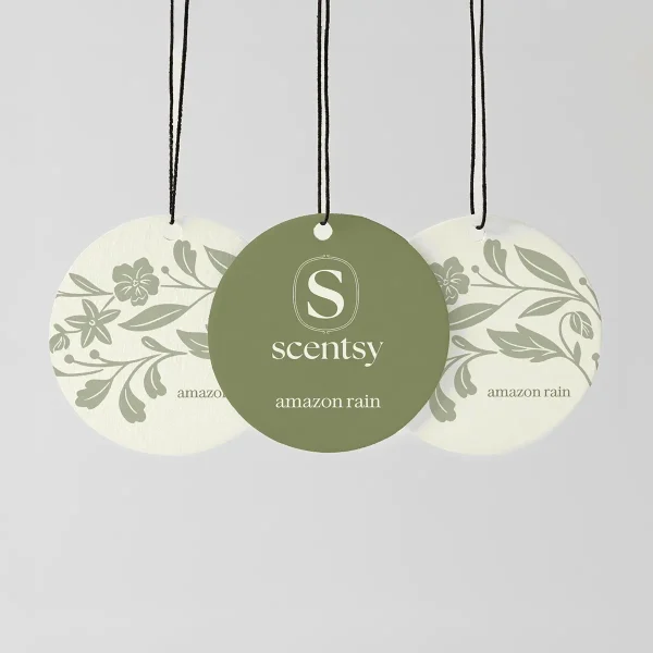 Three circular Scentsy Scent Circles with black strings: a sage-green centre circle and two cream circles with botanical leaf and flower designs, the Amazon Rain Scent Circle 3-pack