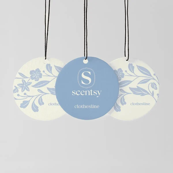 Three circular hanging fragrance discs with black strings, the centre one blue with the Scentsy logo, the two outer ones cream with blue floral patterns, labelled Clothesline Scent Circle 3-pack