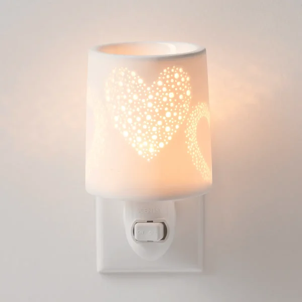 White ceramic plug-in warmer with a heart cutout design casting warm light, the Heart to Heart Mini Scentsy Warmer