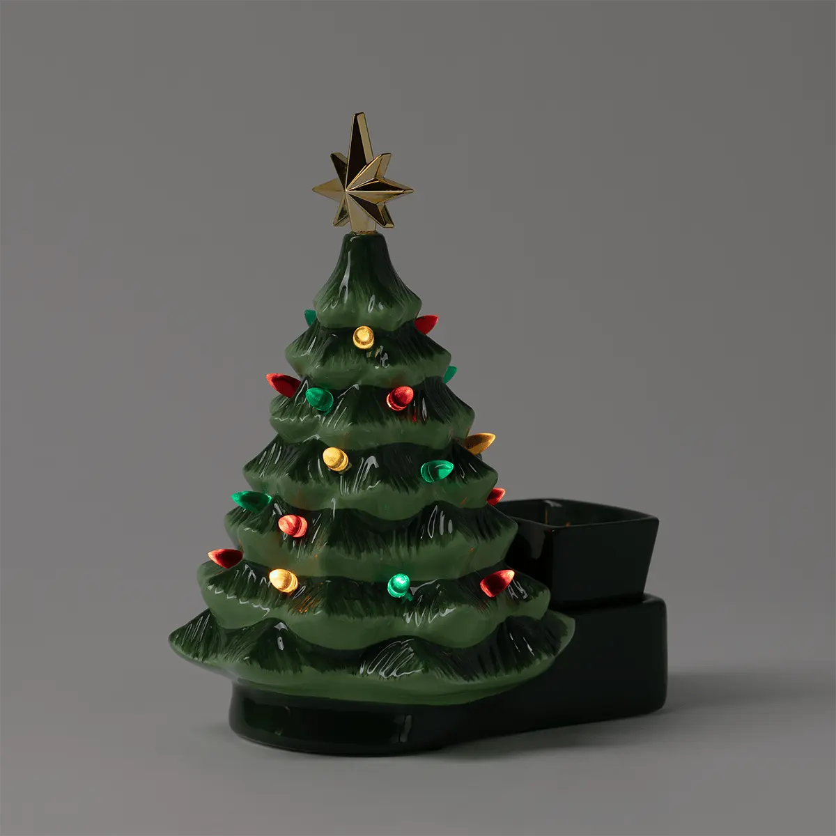 Green ceramic Christmas tree with tiered branches, gold star topper, and coloured ornament decorations, seated on a black base with wax reservoir, the Merry Little Christmas Scentsy Warmer
