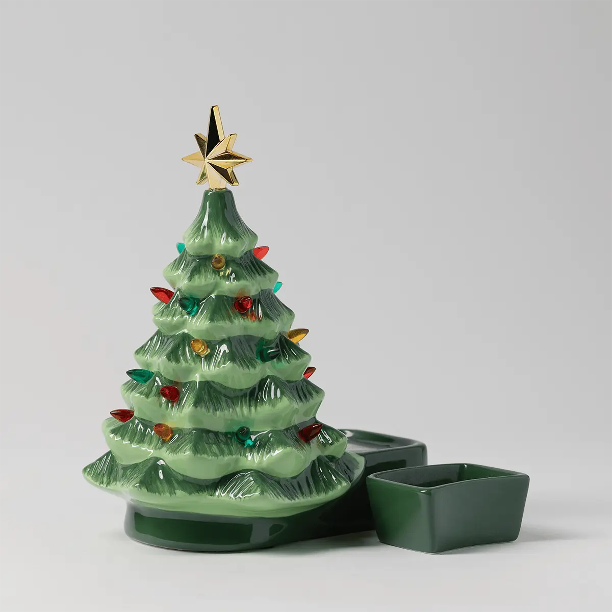 Green ceramic Christmas tree warmer with a gold star on top and multicoloured ornaments, the Merry Little Christmas Scentsy Warmer, shown with two removable wax dishes
