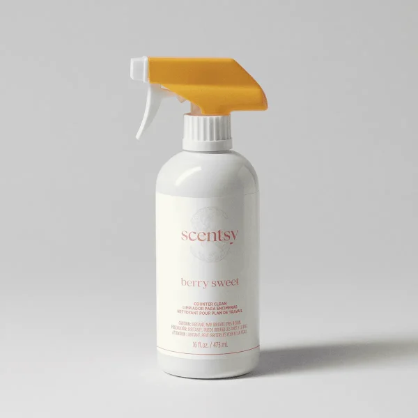 White spray bottle with a gold trigger and nozzle, labelled "scentsy Berry Sweet Counter Clean", 16 fl oz, against a neutral background