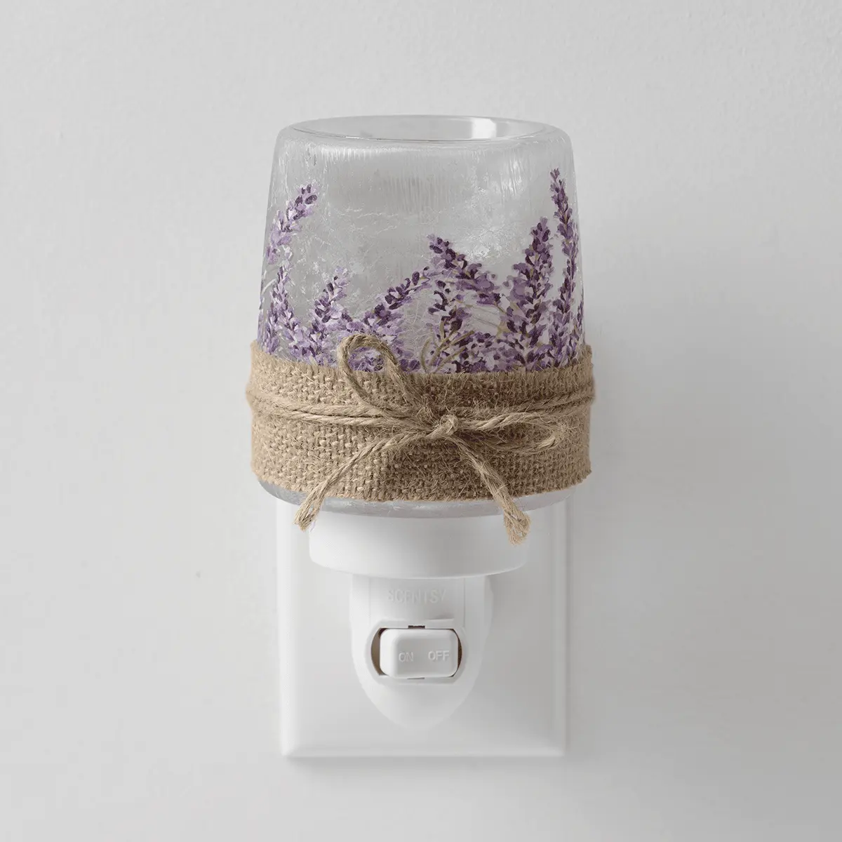 Clear glass mini warmer with purple lavender sprigs design and natural twine bow, mounted on a white wall plug base with on/off switch
