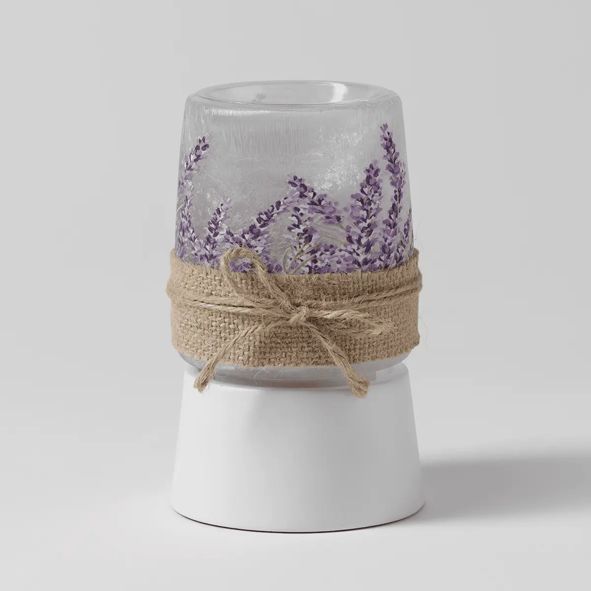 Clear glass mini warmer with purple lavender sprigs printed around the upper section, natural burlap bow accent, and white ceramic base