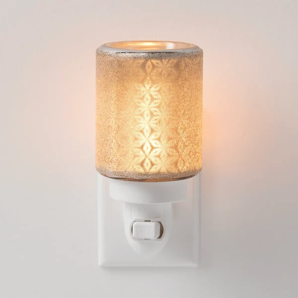 Gold textured cylindrical shade with filigree diamond pattern glowing when lit, mounted on a white wall-plug base with on/off switch, the Fancy Filigree Mini Scentsy Warmer