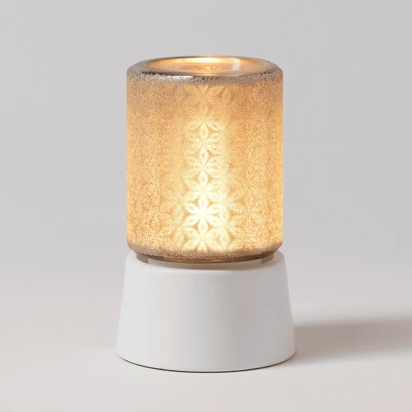 Cylindrical warmer with a textured golden finish and delicate filigree snowflake pattern, illuminated warm glow inside, paired with a white ceramic tabletop base, the Fancy Filigree Mini Scentsy Warmer with Tabletop Base