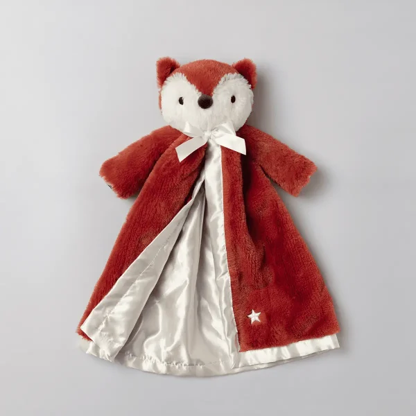 Soft plush fox toy with red-brown fur, cream-coloured face and belly, pointed ears, and black nose, wearing a white satin bow and a red cape with a white star detail and cream satin lining, Finn the Fox Scentsy Blankie Buddy