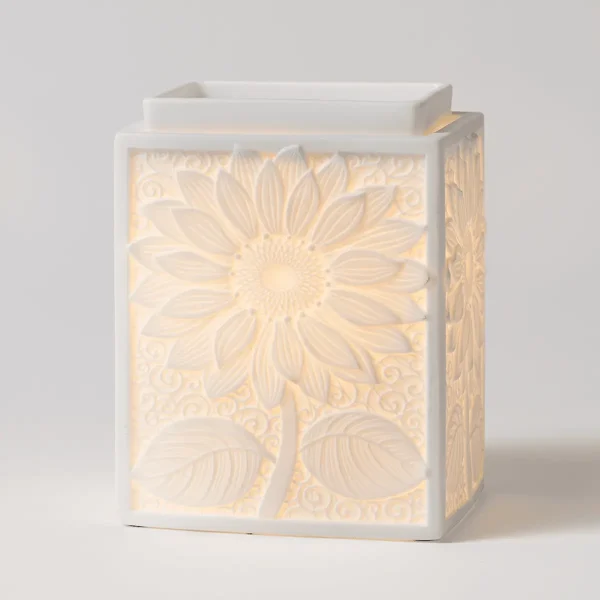 White ceramic warmer with an embossed sunflower and leaf design that glows warm when illuminated, the Sunburst Scentsy Warmer