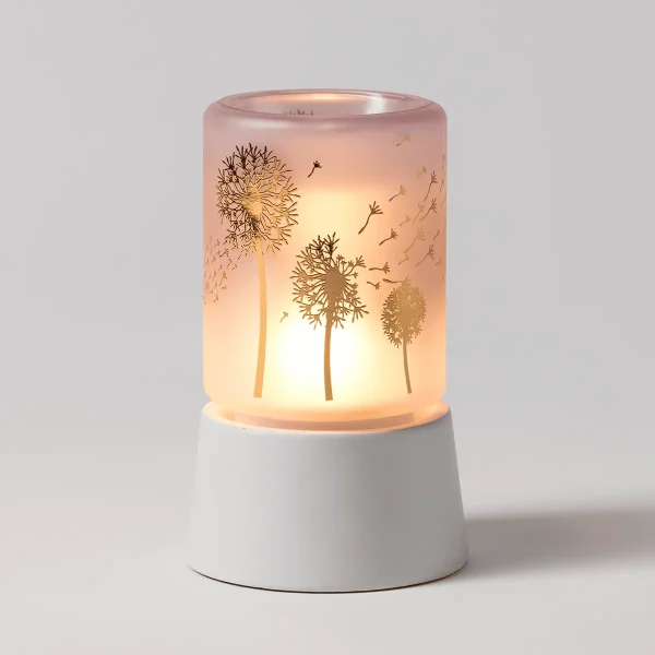 Translucent pink cylindrical warmer with etched dandelion and seedhead design, lit from within with a warm glow, seated on a white ceramic tabletop base, the Wishbloom Mini Scentsy Warmer with Tabletop Base