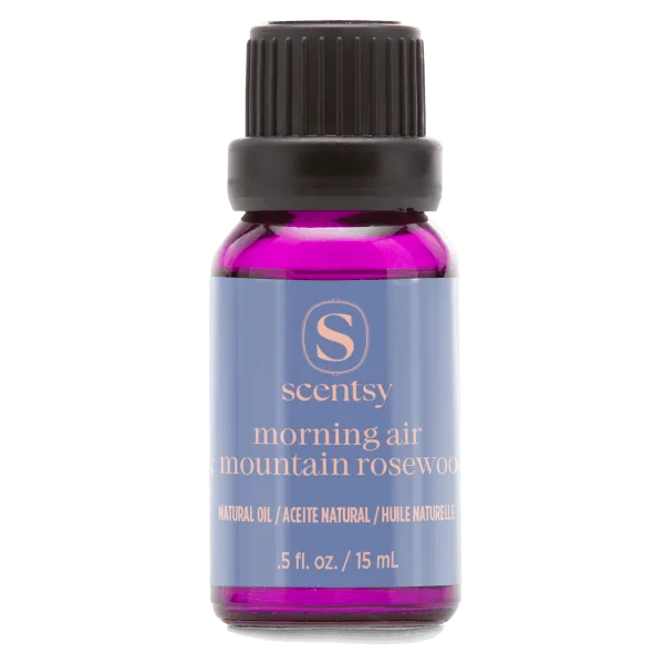 Small glass bottle filled with bright magenta natural oil, topped with a black ridged cap, featuring a periwinkle-blue label with rose-gold Scentsy branding for Morning Air & Mountain Rosewood Natural Oil Blend