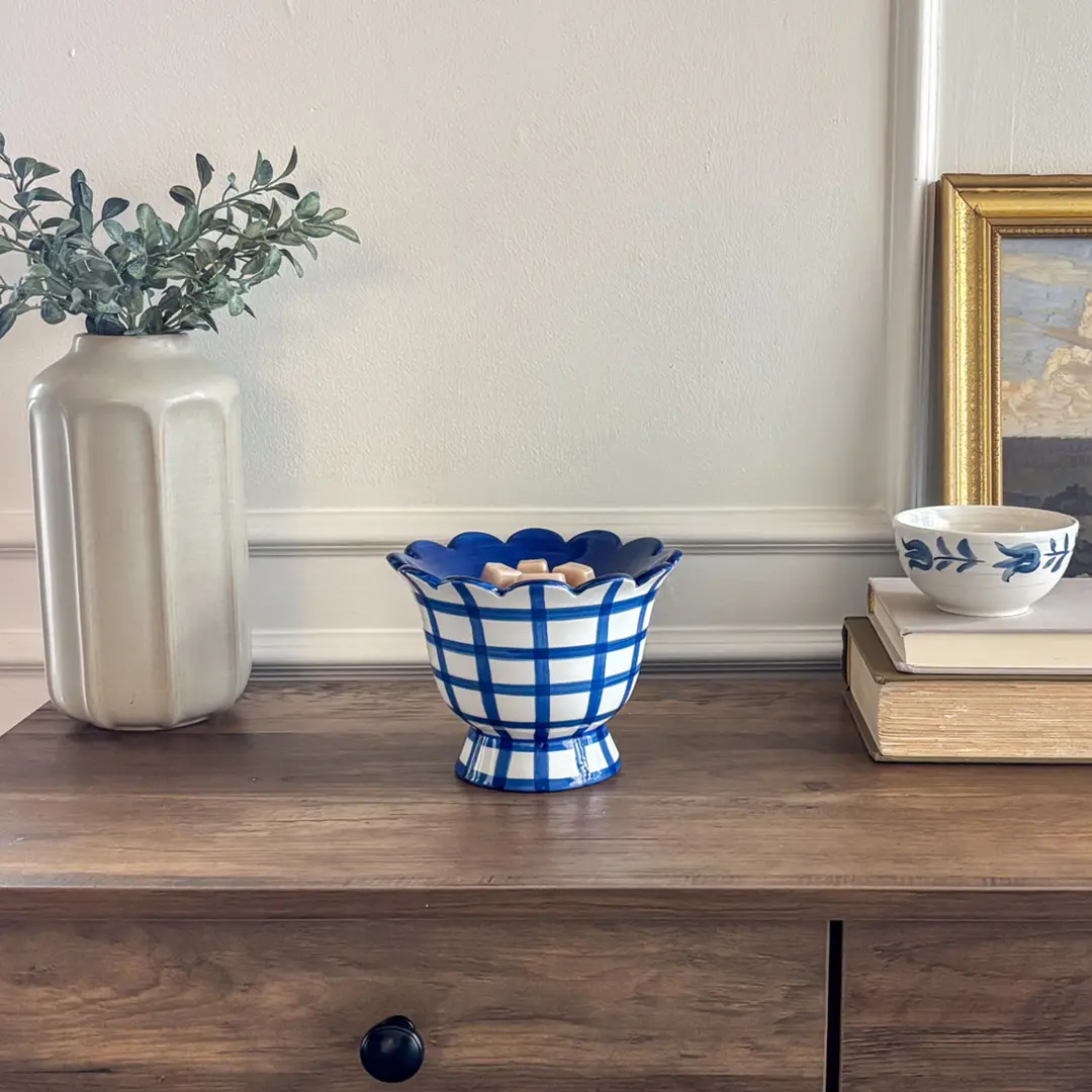 Pedestal-style ceramic warmer with scalloped rim and blue gingham pattern on white glaze, the Bluebell Gingham Scentsy Warmer, styled on a wooden shelf