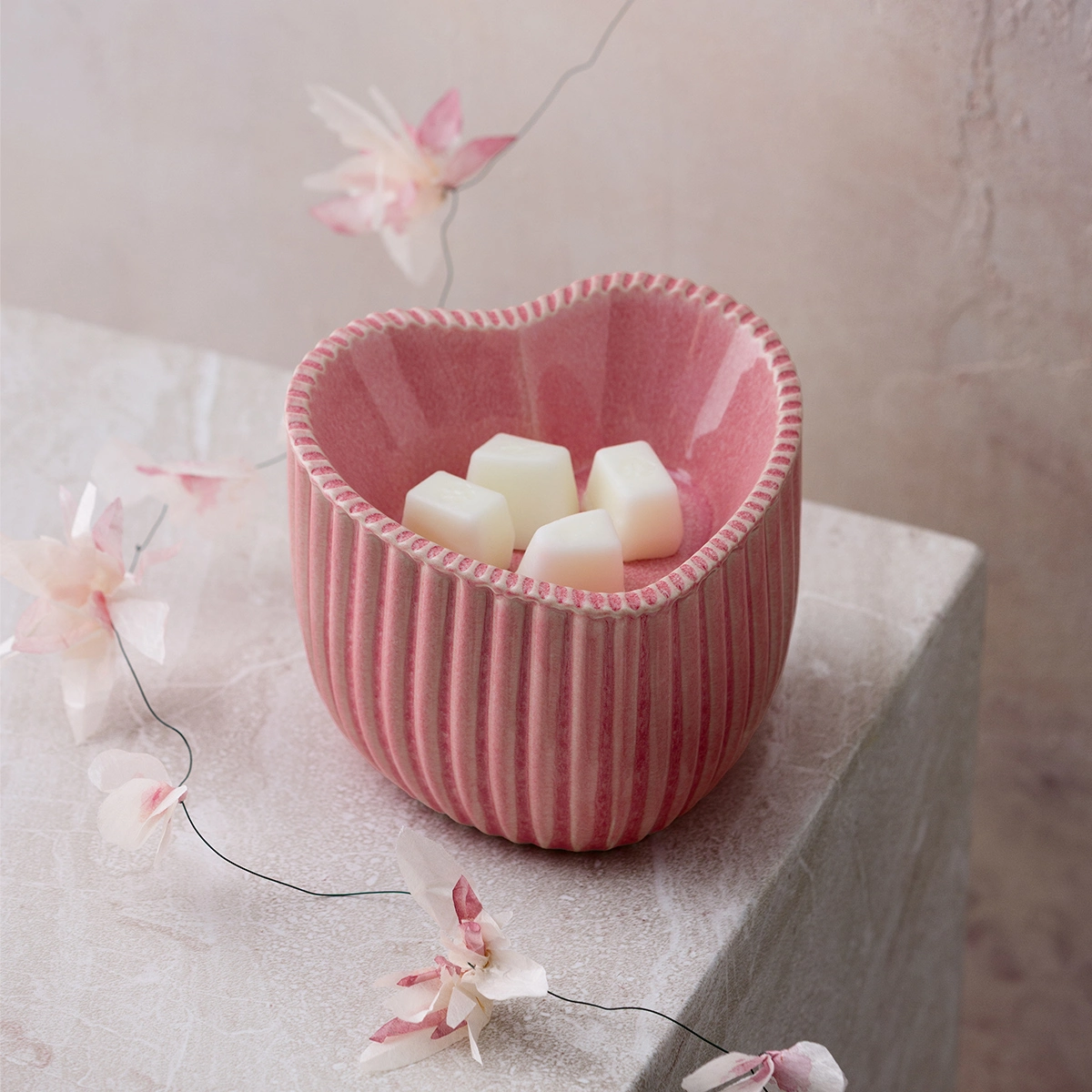 Pink heart-shaped Scentsy Warmer with vertical ribbed texture and braided trim, filled with cream wax melts, the Heart of Hope Scentsy Warmer