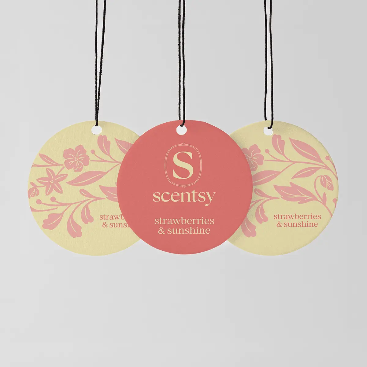 Strawberries & Sunshine Scent Circle 3-pack - Three circular hanging fragrance tags with black strings: two pale yellow tags with pink floral designs and "strawberries & sunshine" text, flanking a coral-pink central tag with the Scentsy logo and "Strawberries & Sunshine Scent Circle 3-pack" branding