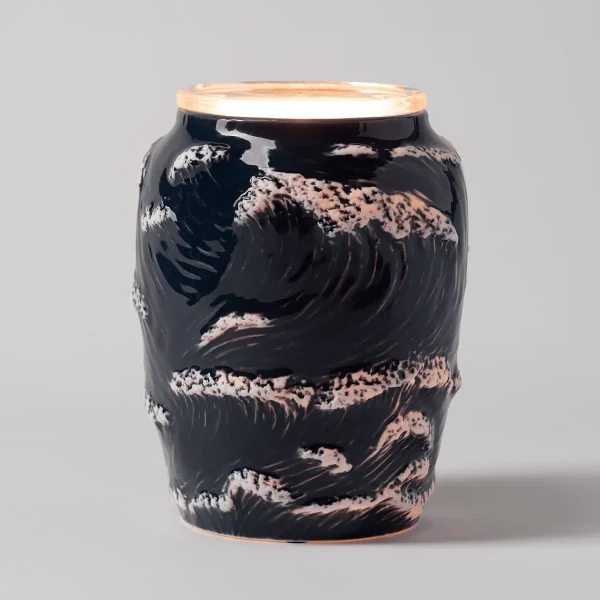 Black ceramic warmer with sculpted wave patterns in cream and terracotta tones, topped with a cream-coloured lid, the Ocean Crest Scentsy Warmer