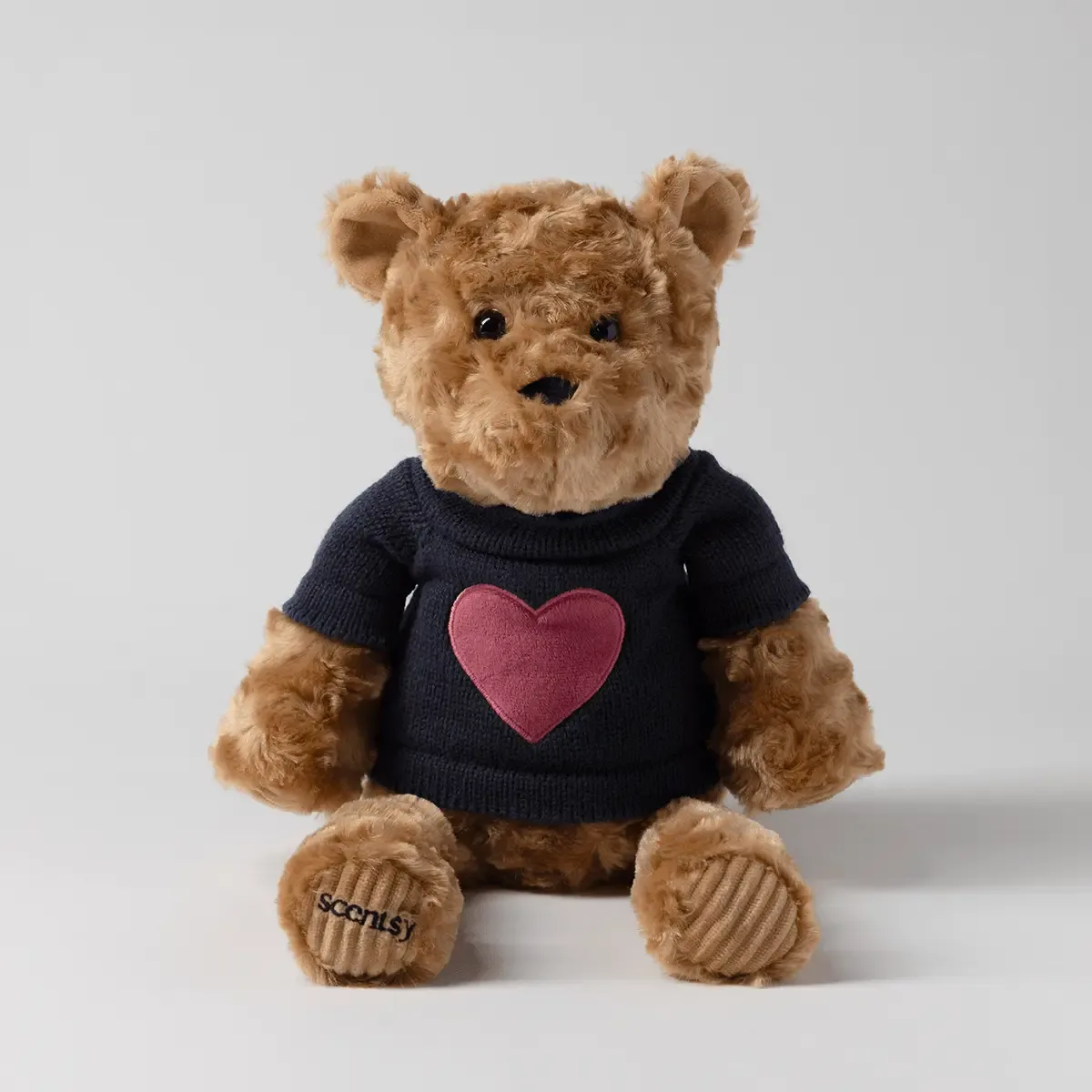 Soft tan plush bear with black nose and eyes, wearing a dark navy knit sweater with a pink heart, Banner the Bear Scentsy Buddy, with embroidered paws