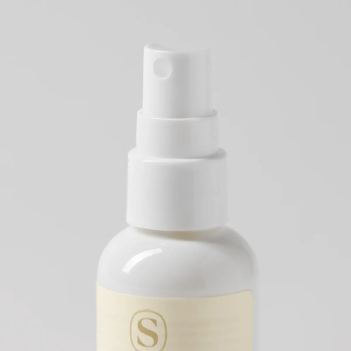White spray bottle with cream-coloured label bearing an embossed "S" logo, the Silver-N-Gold Travel Spray