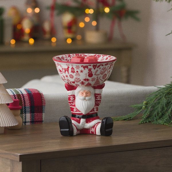 Christmas Keeper Scentsy Warmer (Copy) - Red and white ceramic Santa figure with white beard and festive outfit holding a red and white decorative bowl filled with red wax cubes, the Christmas Keeper Scentsy Warmer, displayed on a wood surface with holiday décor in the background