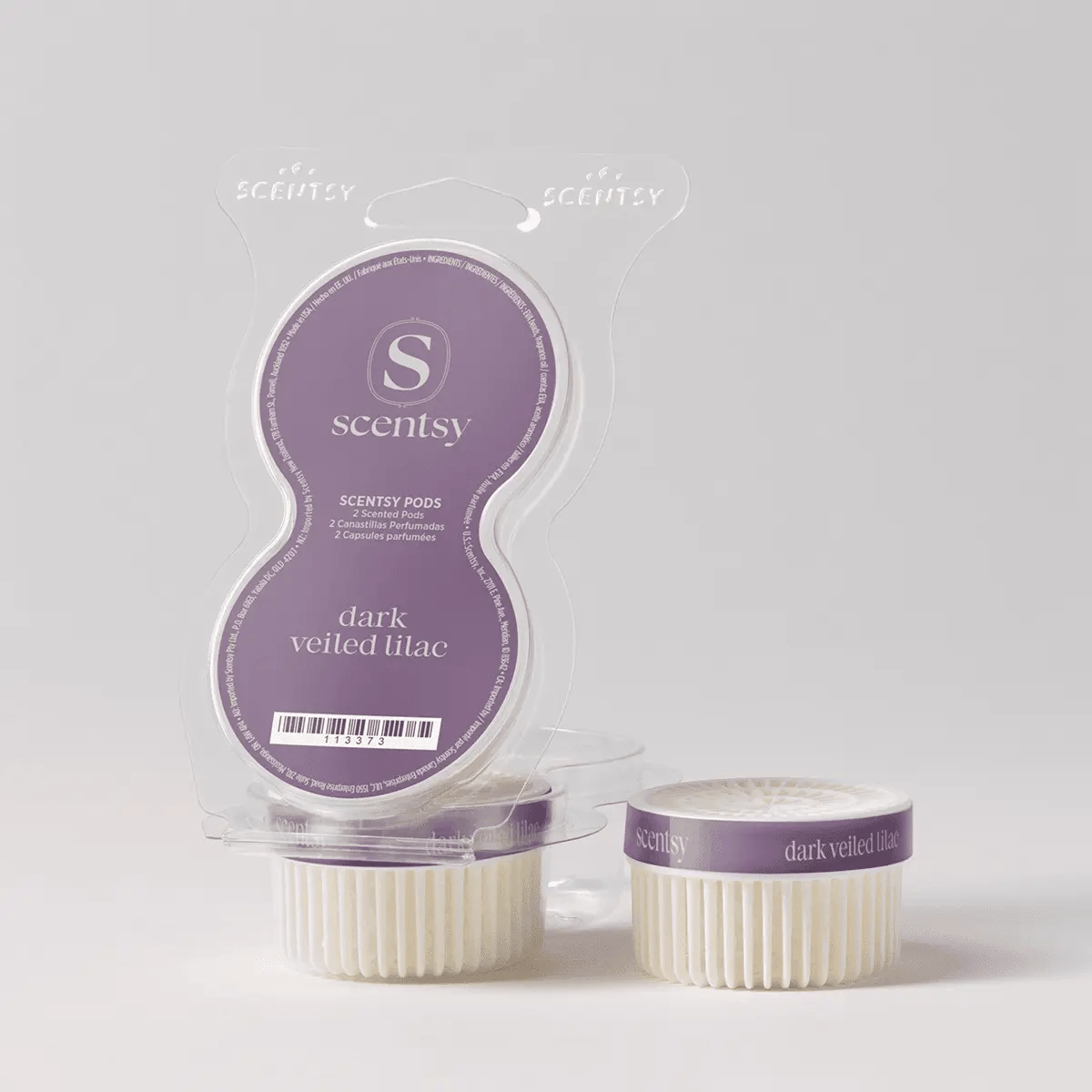 Clear clamshell packaging containing two cream-coloured ridged wax pods with purple bands labelled Dark Veiled Lilac Scentsy Pods, displayed with one pod outside the package