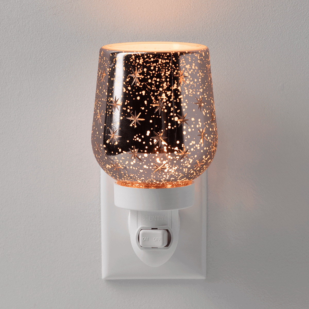 Rose gold speckled dome-shaped shade with scattered star cutouts over white plug-in base with on/off switch, the Frosted Flurry Mini Scentsy Warmer