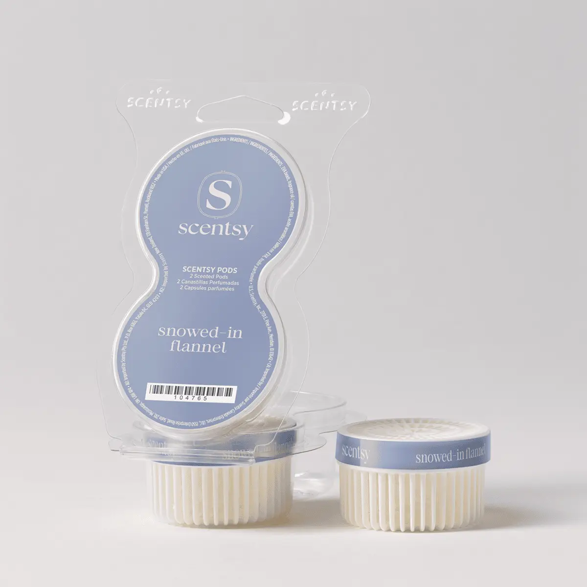 Two cream-coloured ridged Scentsy Pods with blue bands labeled "snowed-in flannel" displayed beside their clear clamshell packaging, the Snowed-In Flannel Scentsy Pods
