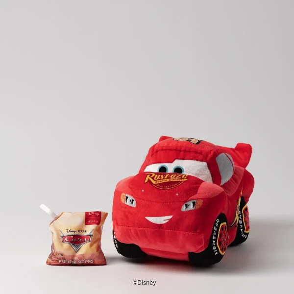 Red plush toy car with white eyes and smile, black wheels and yellow "Radiator Springs" text, Disney And Pixar Lightning Mcqueen Scentsy Buddy, displayed next to a Radiator Springs Scentsy wax packet