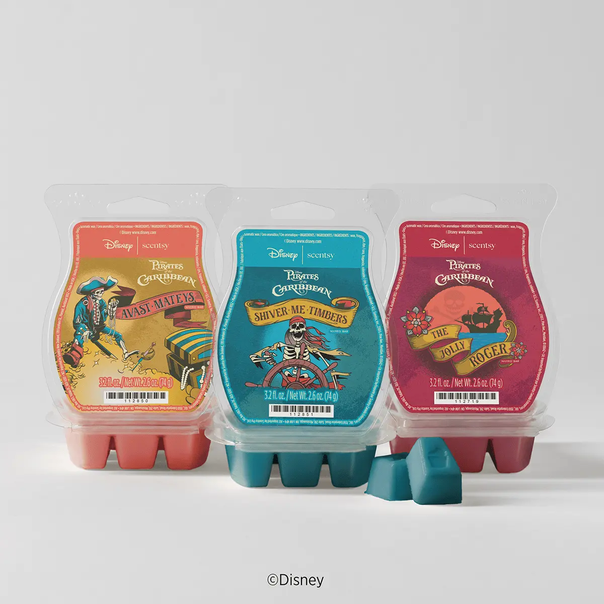 Three Scentsy Wax bars in Pirates of the Caribbean designs: gold packet with red border (Avast Mates), turquoise packet (Shiver Me Timbers), and magenta packet (The Jolly Roger), with matching coloured wax cubes displayed in front