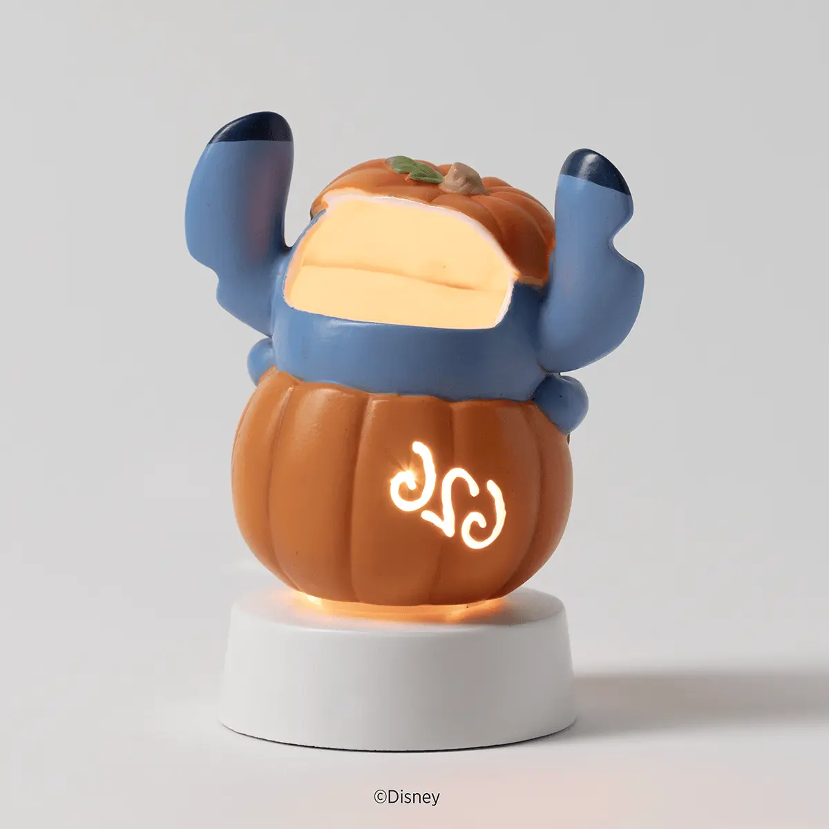Stitch character figurine warmer in orange pumpkin form with blue arms raised, cream-coloured wax reservoir, and white tabletop base, the Disney Stitch: Pumpkin Trouble Mini Scentsy Warmer