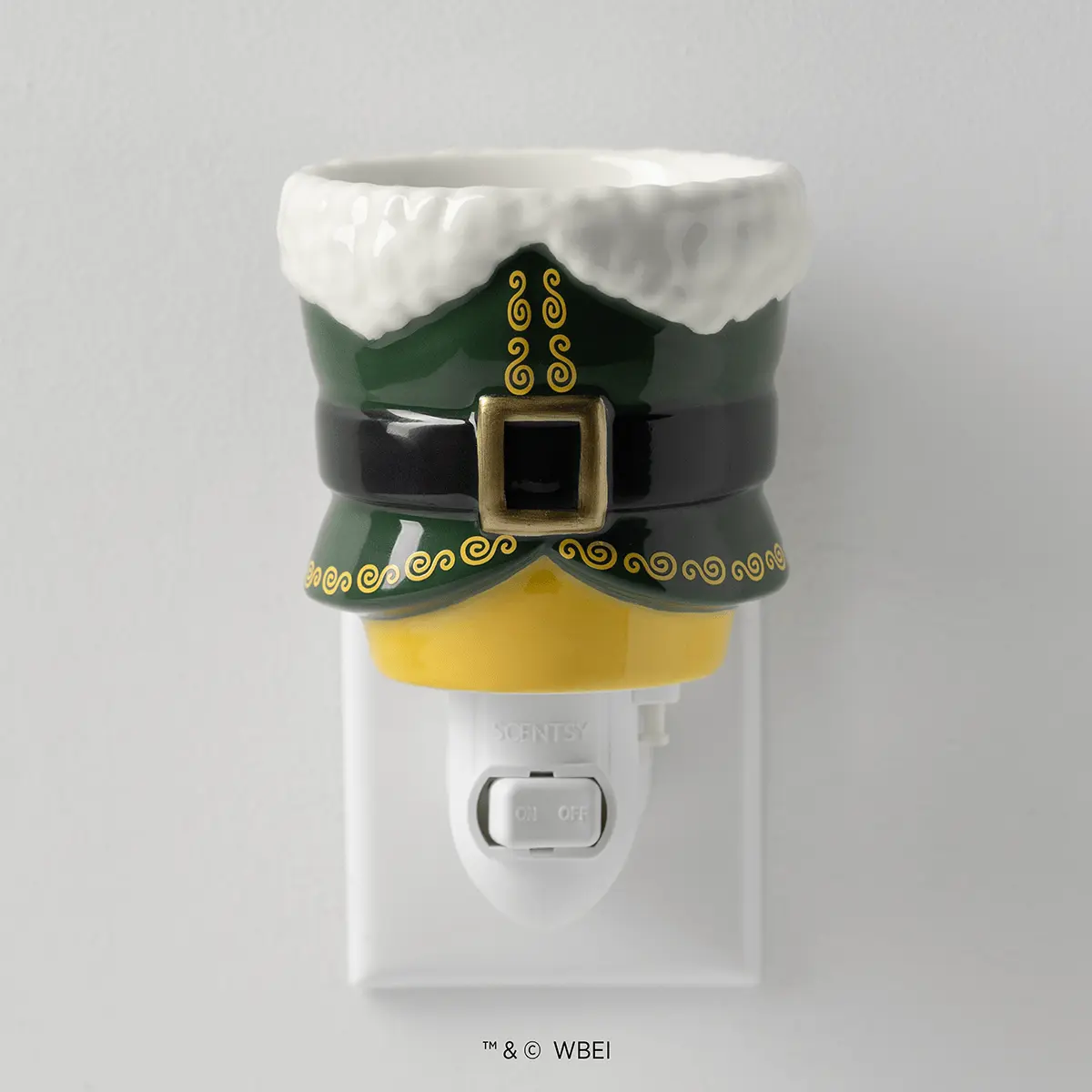 White ceramic wall plug warmer styled as an elf with a green hat trimmed in white faux fur, gold curled details, black belt with gold buckle, and yellow shirt, the Elf: Buddy’s Christmas Joy Mini Scentsy Warmer