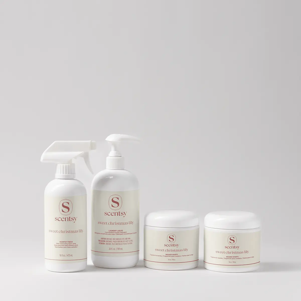 Four white Scentsy laundry products in the Sweet Christmas Lily scent, part of the Holiday Laundry Bundle: a trigger spray bottle, a pump bottle of laundry liquid, and two jars of washer whiffs, arranged in a row against a neutral background